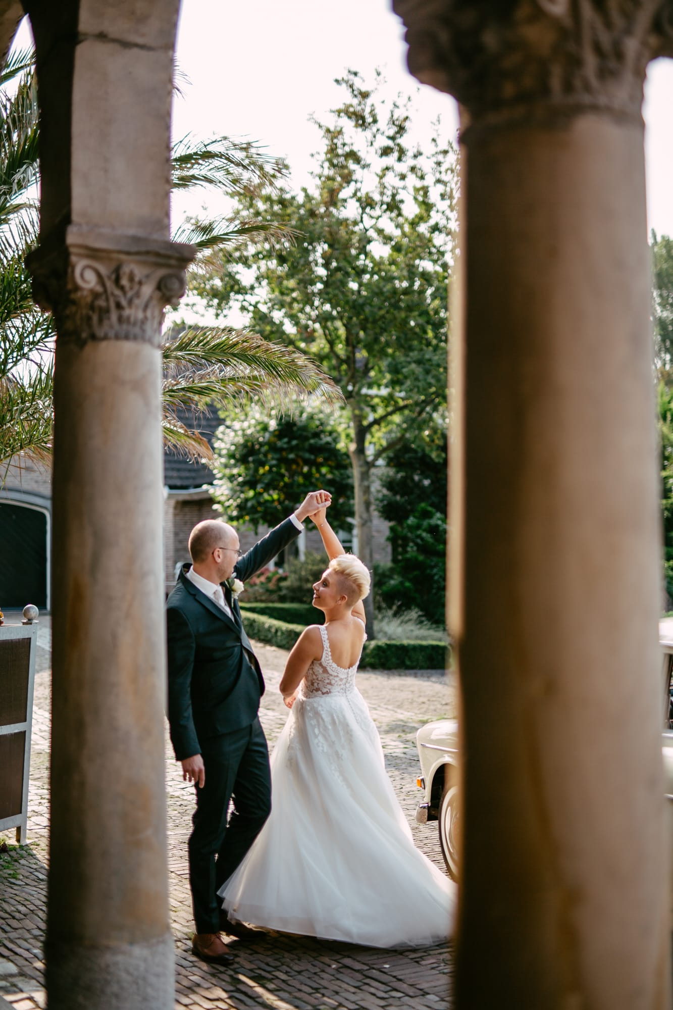 A bride and groom dancing elegantly in front of a beautiful arch.