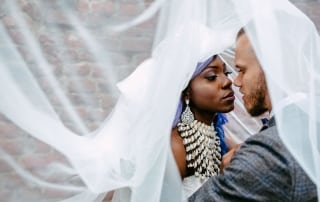 Een bruid en bruidegom omhelzen elkaar onder een sluier op hun Trouwfoto's.