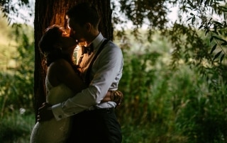 Trouwfotos: Een bruid en bruidegom die elkaar onder een boom knuffelen en het intieme moment van hun speciale dag vastleggen.