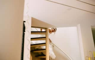 Een bruid loopt elegant de trap op in haar trouwjurk, prachtig vastgelegd op trouwfoto's.
