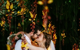 Op hun trouwdag kust een bruid en bruid elkaar onder een prachtige bloemenboog.