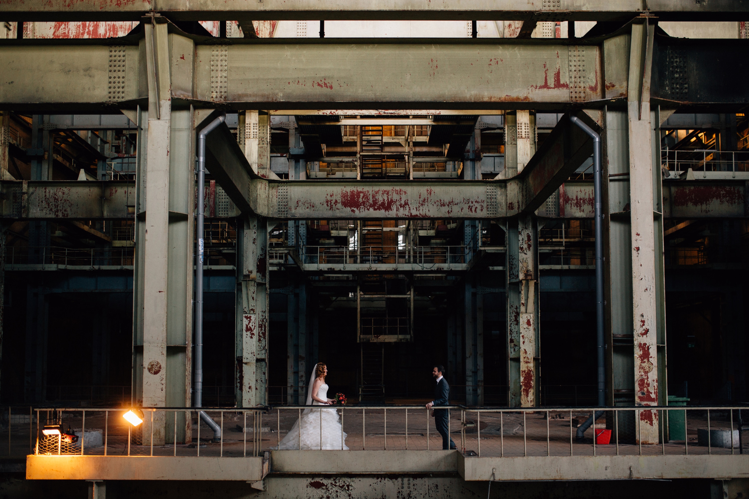 A bride and groom stand in front of an industrial building in Photo locations south holland.