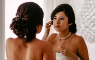 Een bruid in Den Haag doet haar make-up op voor een spiegel.