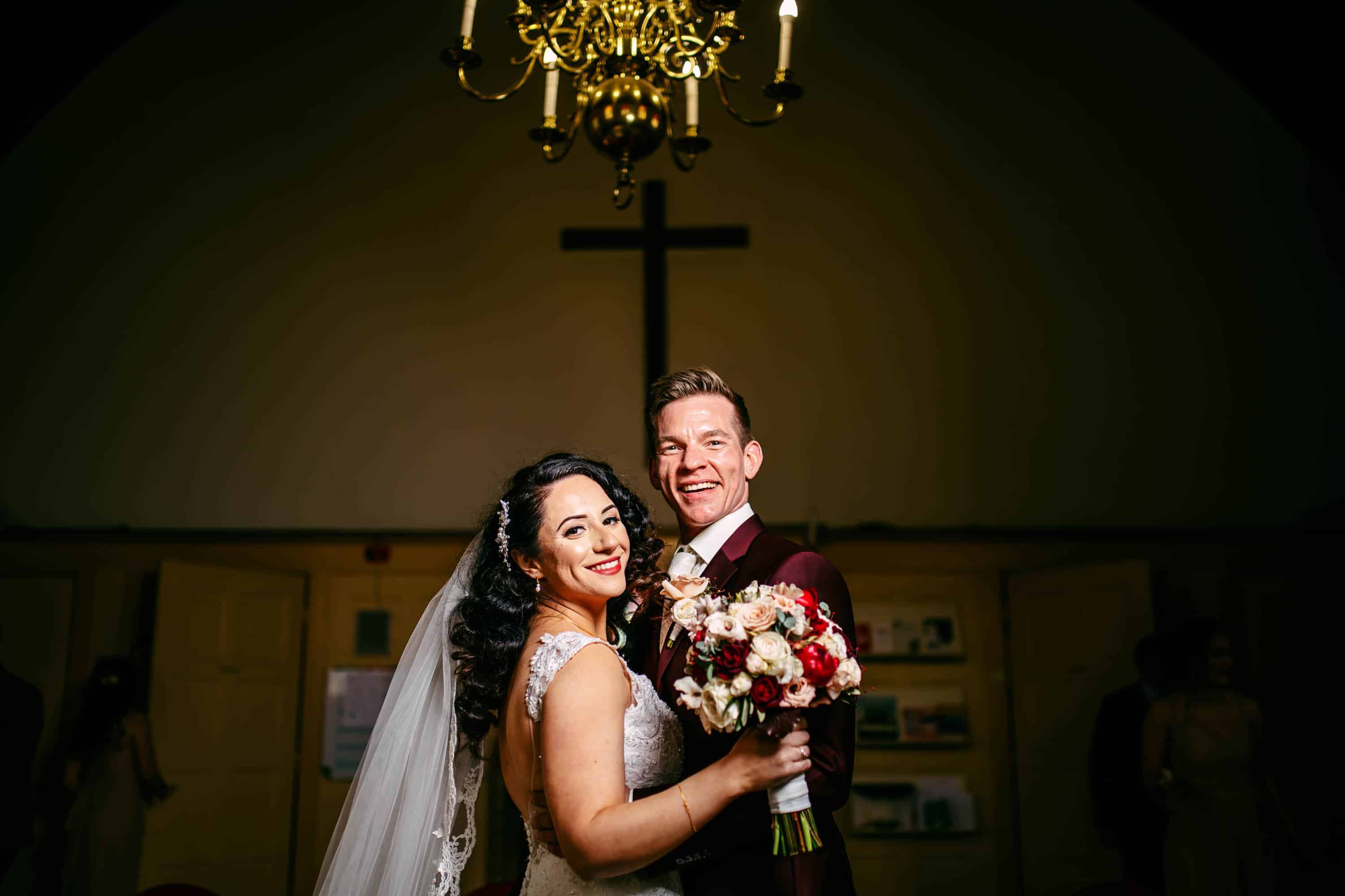 A bride and groom pose for a photo in a church.