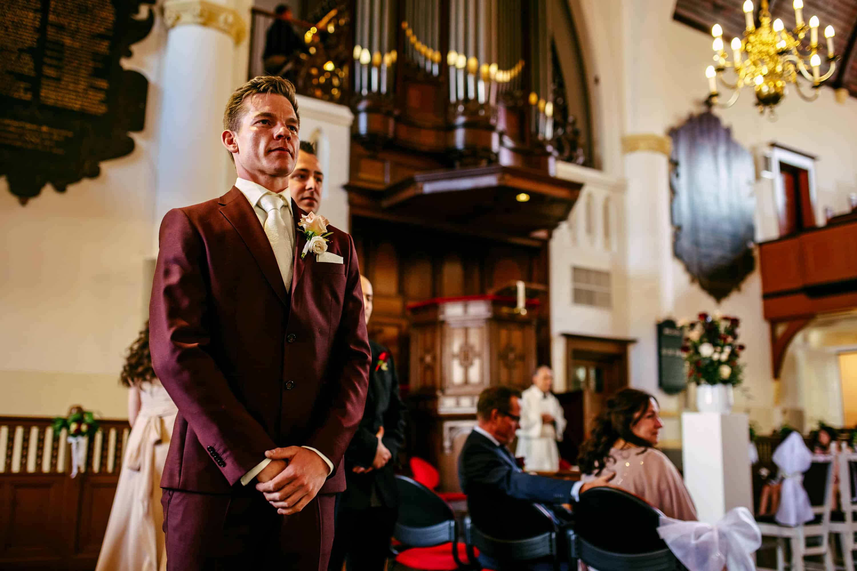 A man in a suit walks down the aisle of a church.