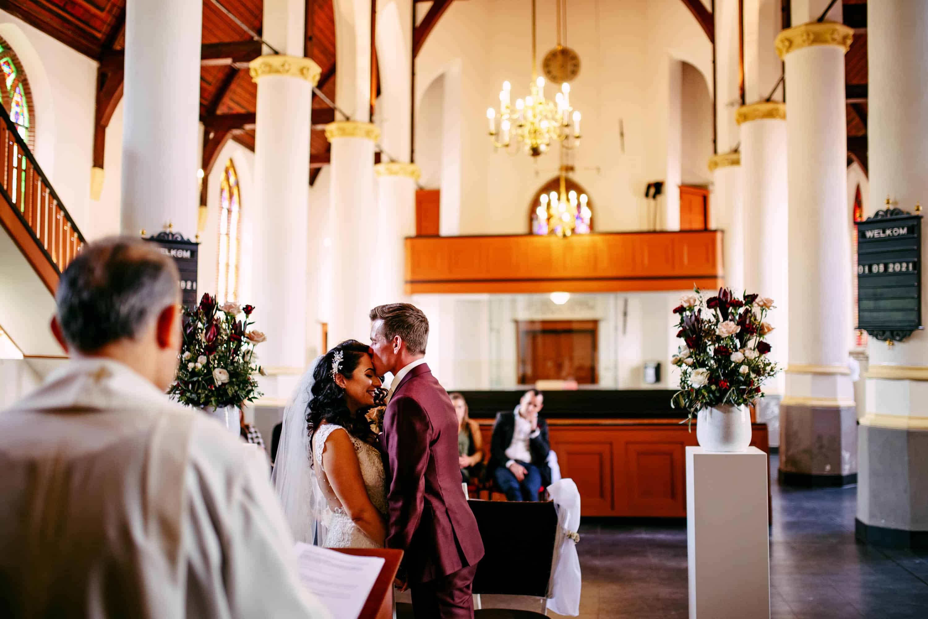 A bride and groom kiss in a church.