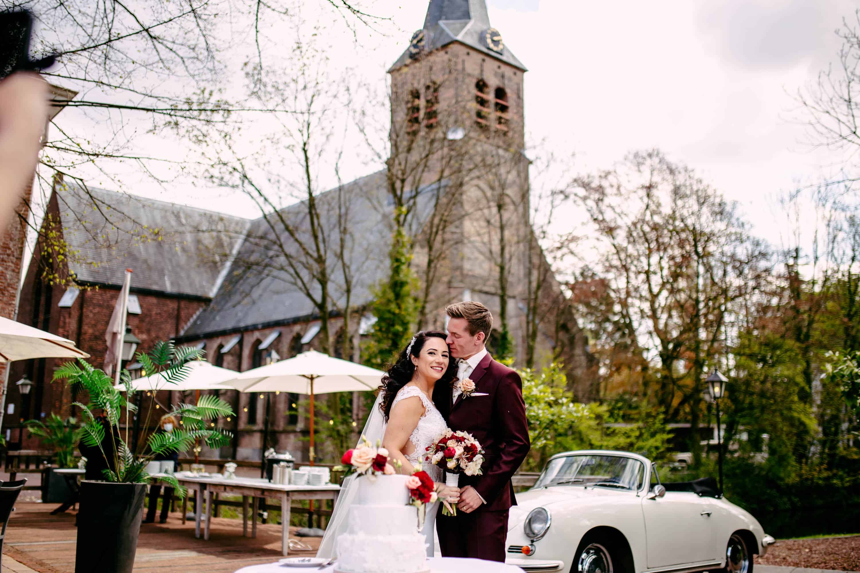 A bride and groom kiss in front of a church.