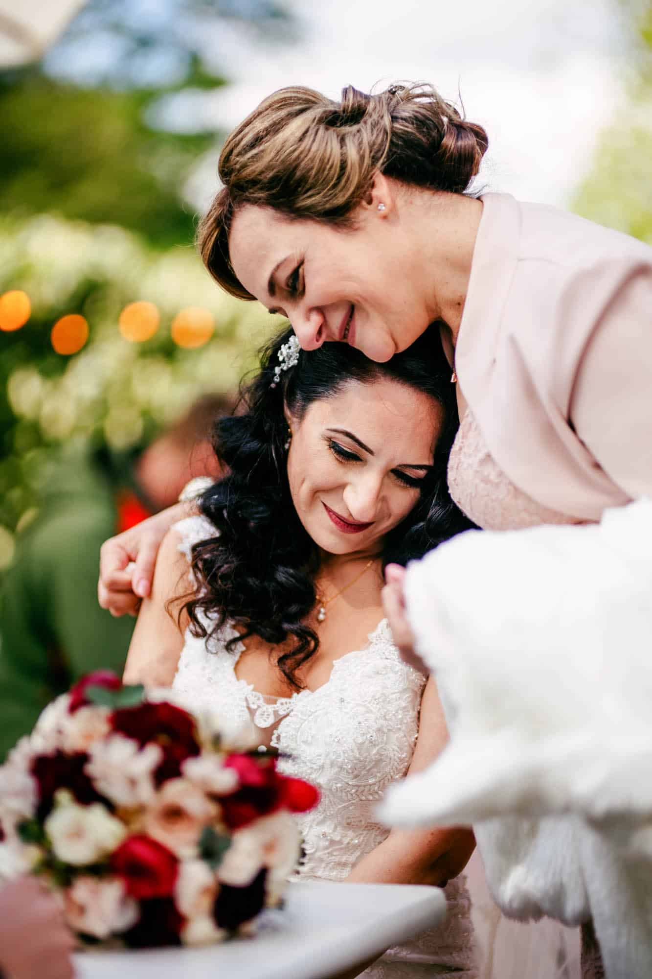 A bride and her mother hug each other at a wedding.
