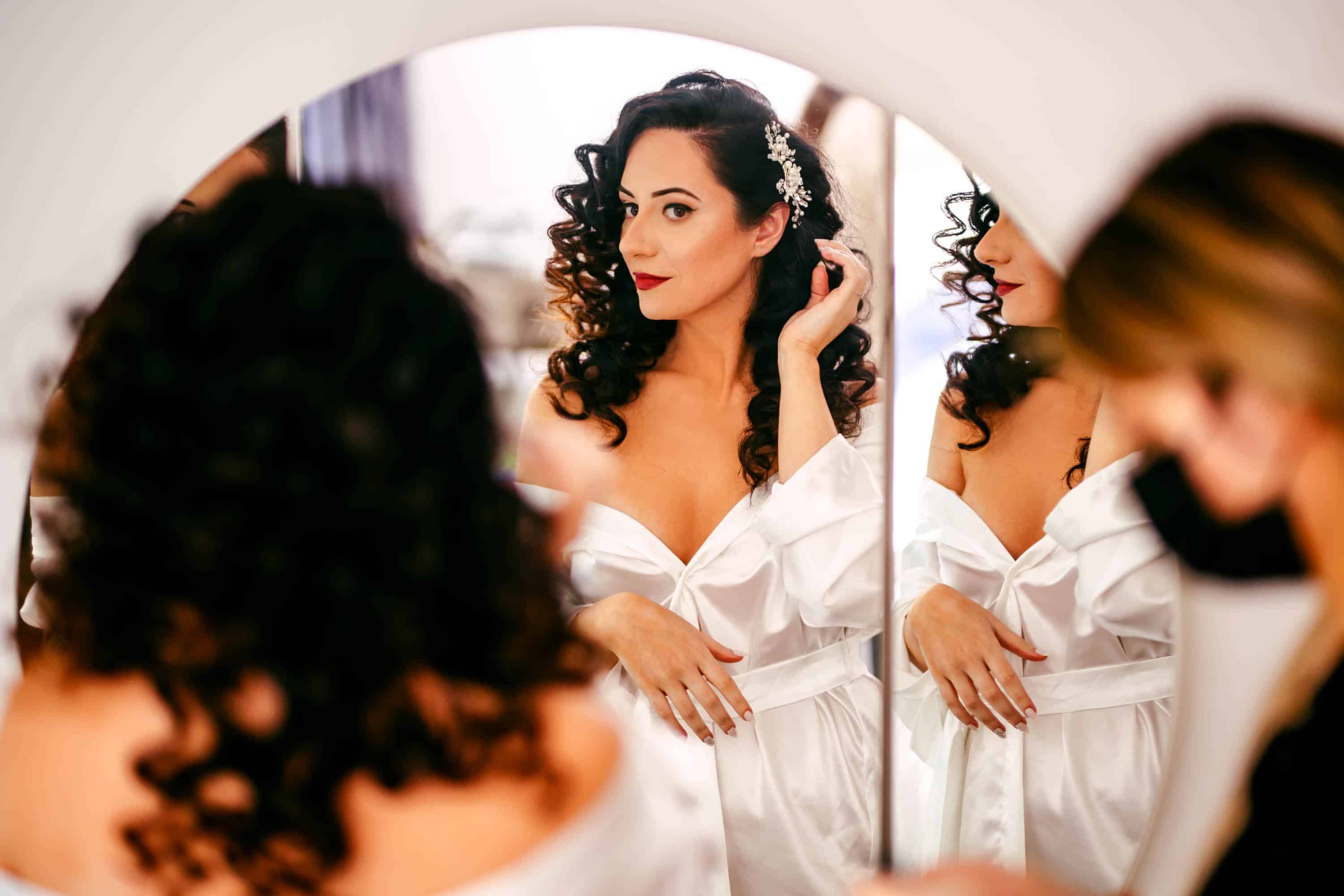 A bride gets ready in front of a mirror.