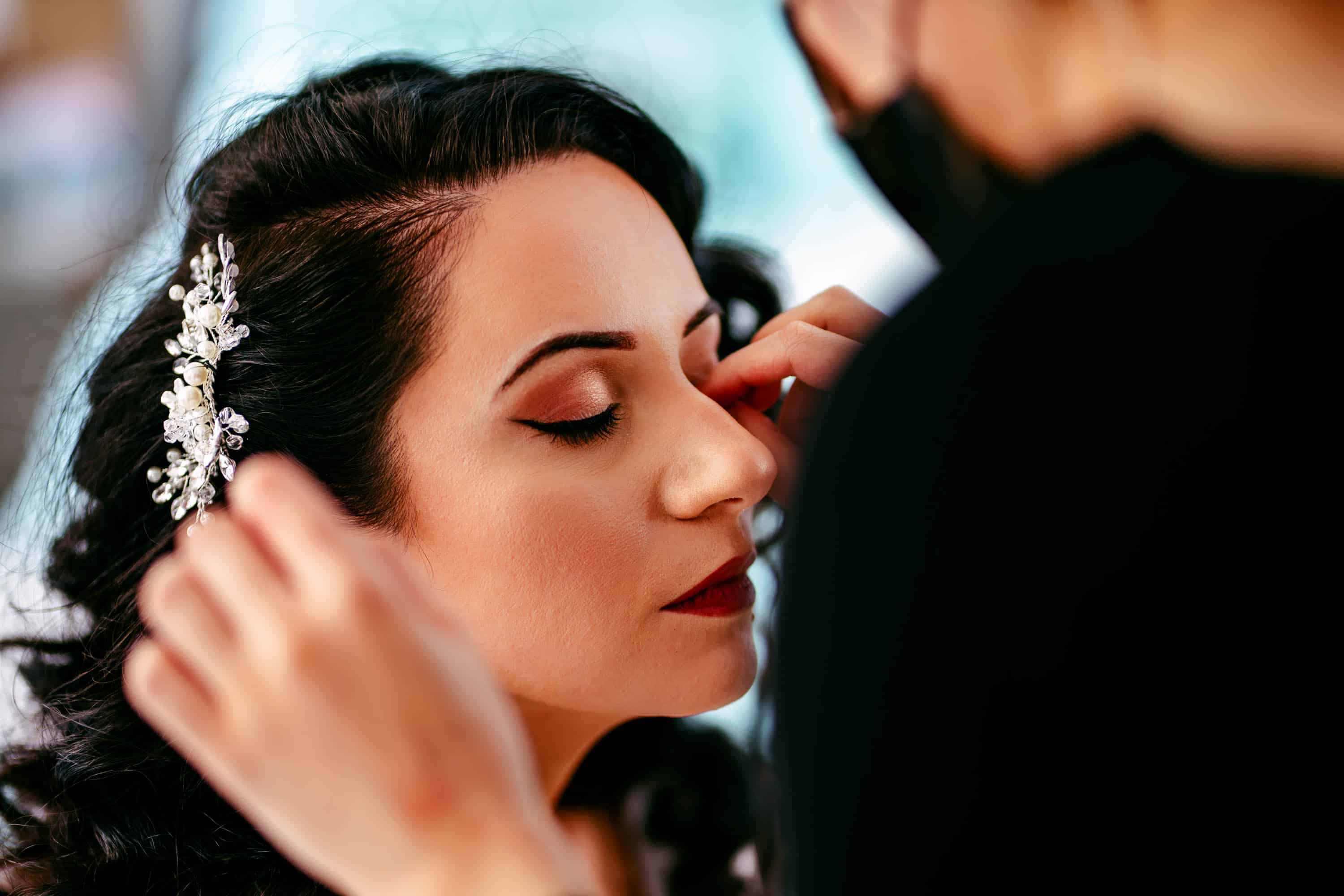 A bride having her make-up done by a make-up artist.