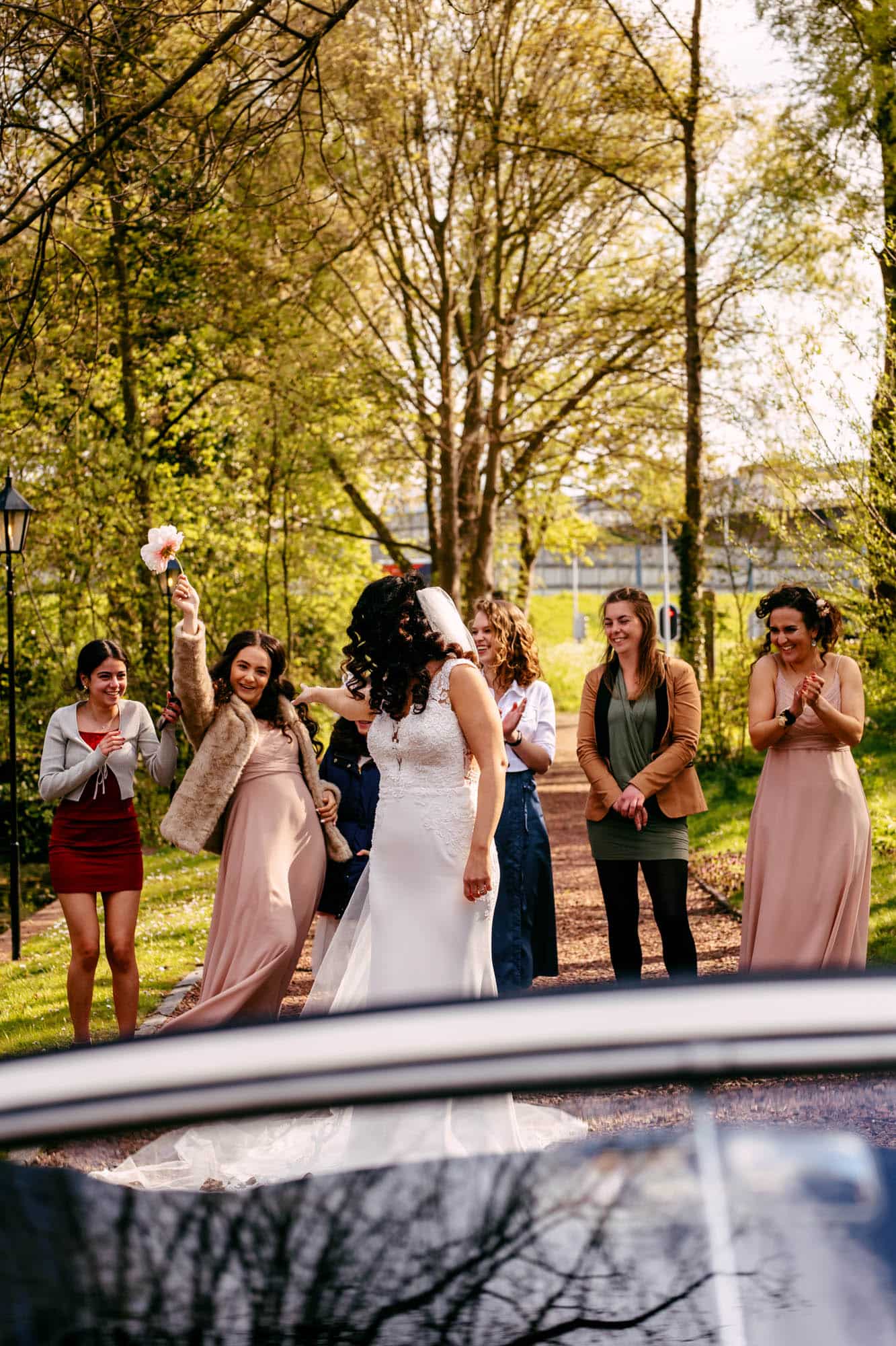 A bride and her bridesmaids get out of a car.