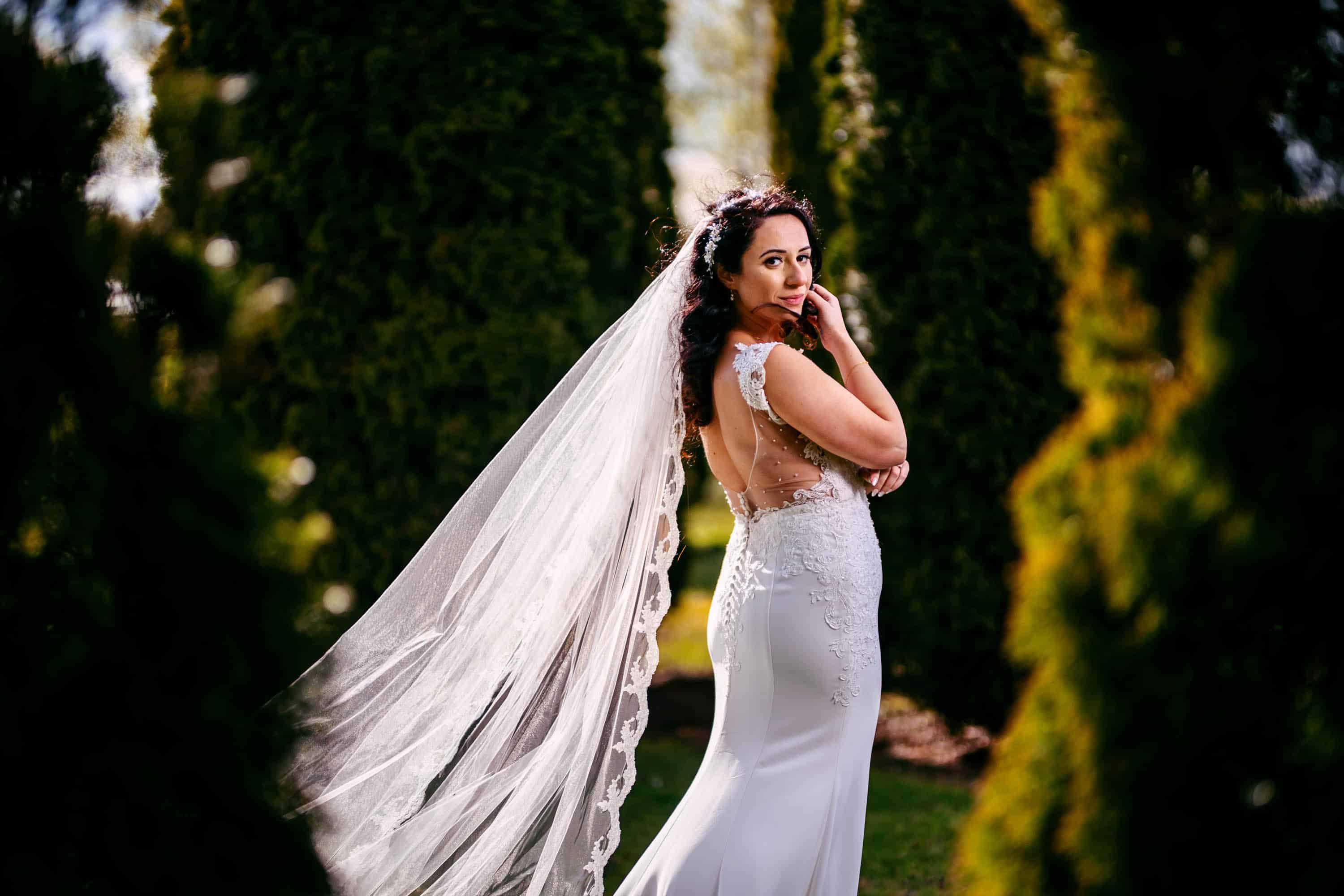 A bride poses in front of a tree in a garden.