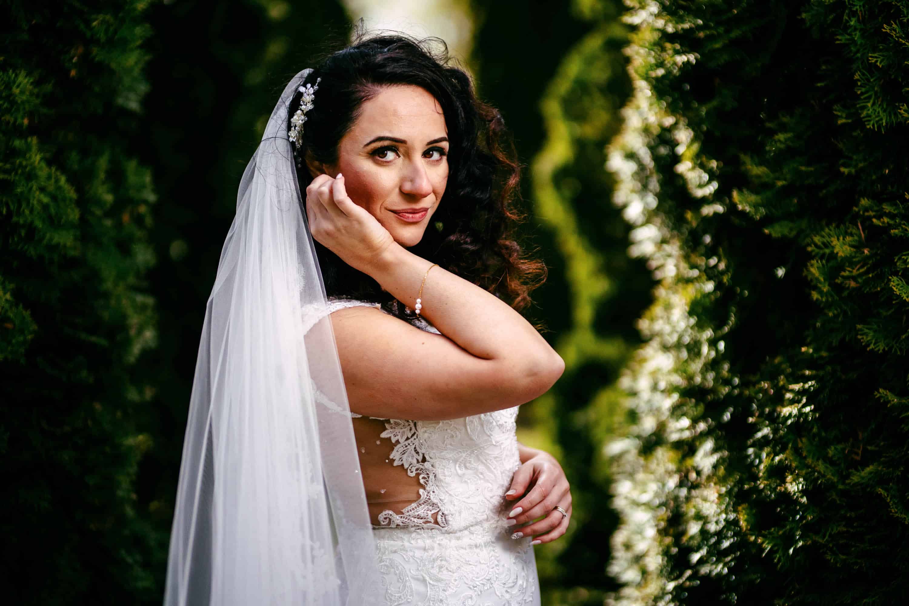A bride poses for a photo in a grove of trees.