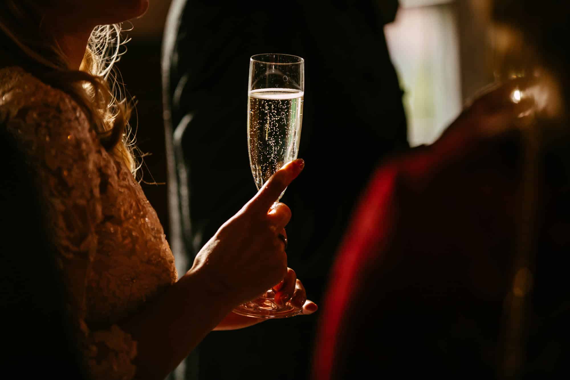 In het elegante Het Koetshuis Rotterdam houdt een vrouw sierlijk een glas champagne vast.
