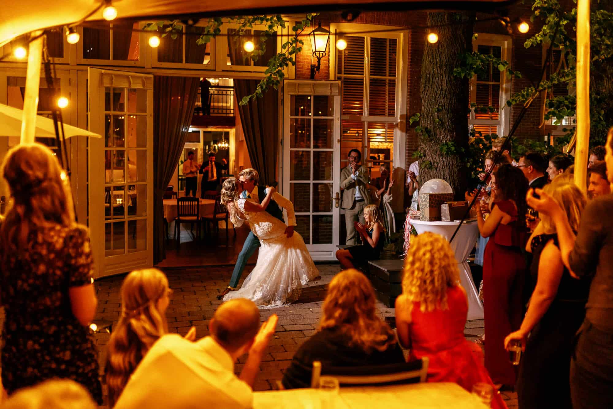 Een bruid en bruidegom dansen op een trouwlocatie buiten in het Rotterdamse Het Koetshuis.