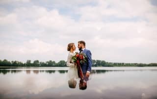 Een bruid en bruidegom staan voor een meer.