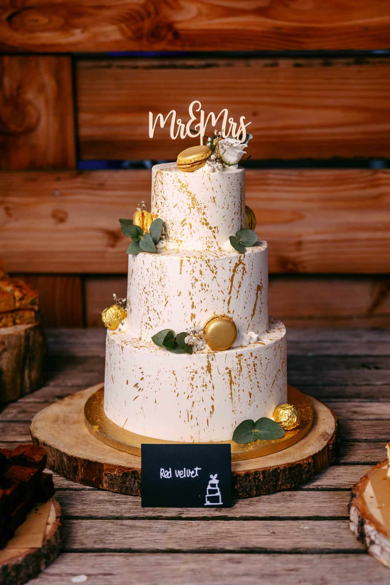 A wedding cake stands on a wooden table.