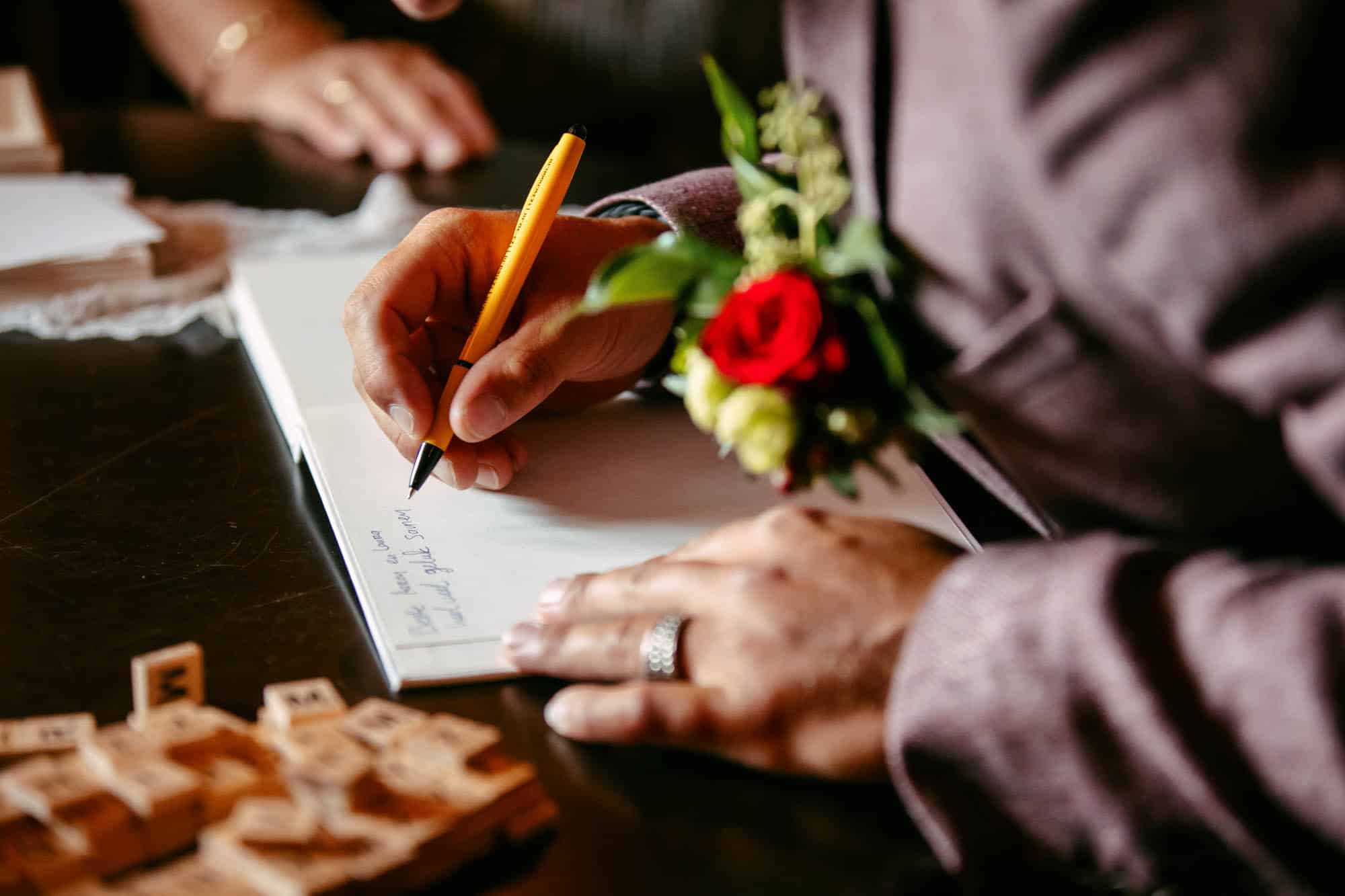 A man in a suit writes a letter on a piece of paper.