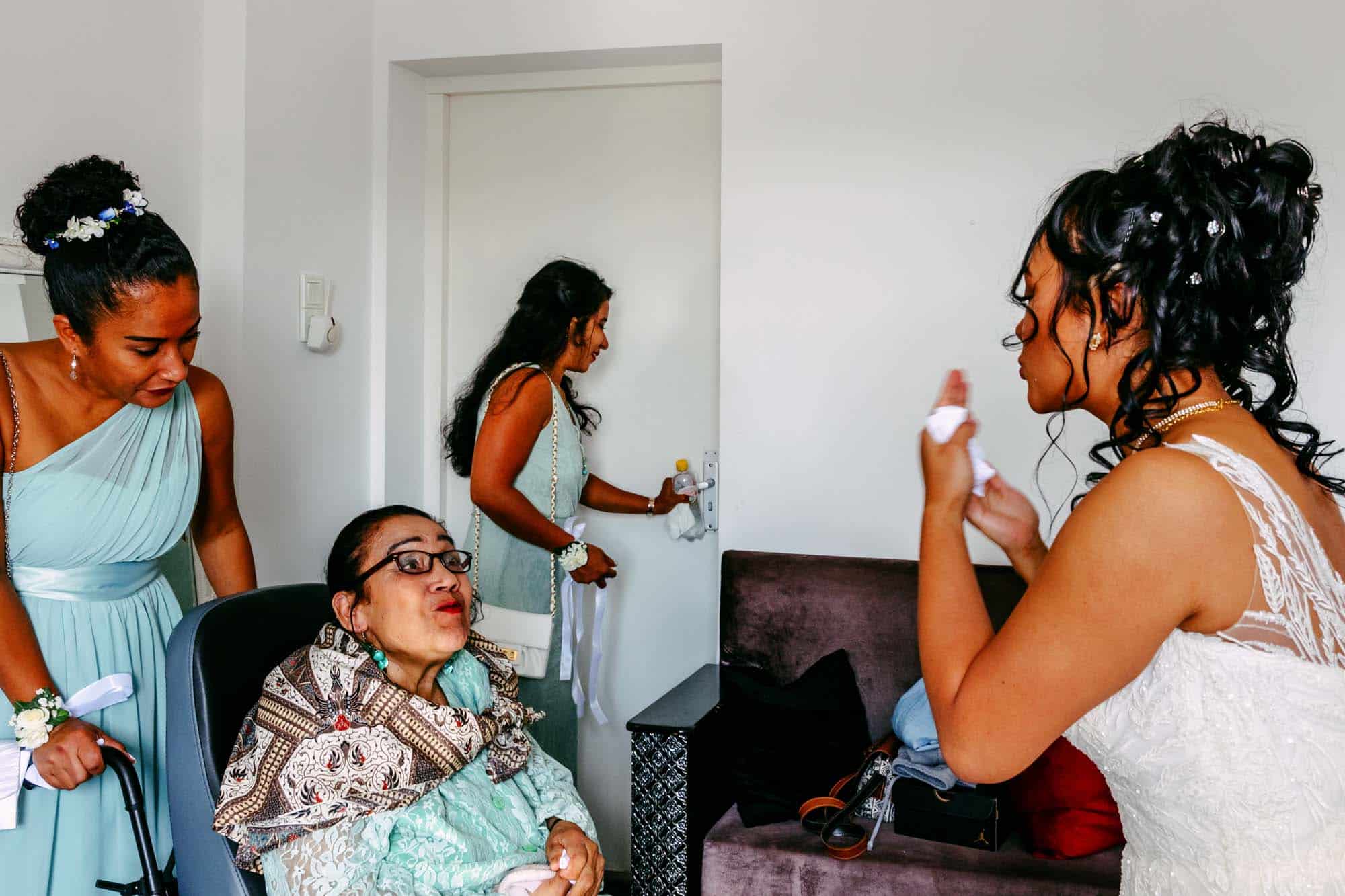 Bruidsmeisjes maken zich klaar in een kamer met een vrouw in een rolstoel en maken bijzondere trouwfoto's.