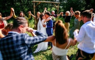 Een groep mensen die danst in een veld en bijzondere trouwfoto's maakt.
