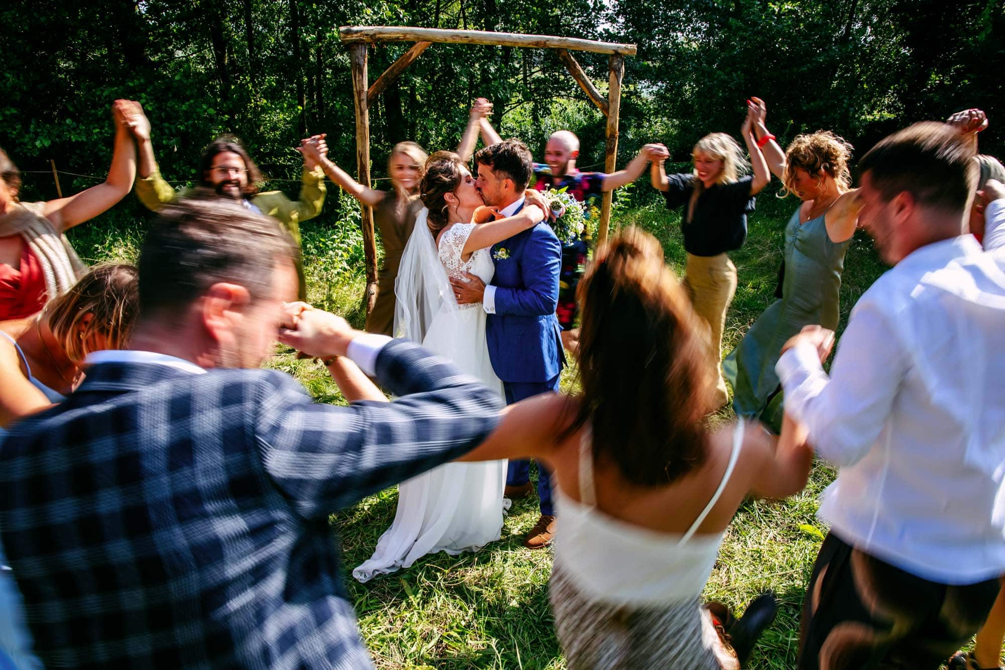 Een groep mensen die danst in een veld en bijzondere trouwfoto's maakt.