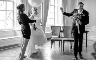 Een bruid en bruidegom houden ballonnen vast in een kamer, waardoor bijzondere trouwfoto's ontstaan.