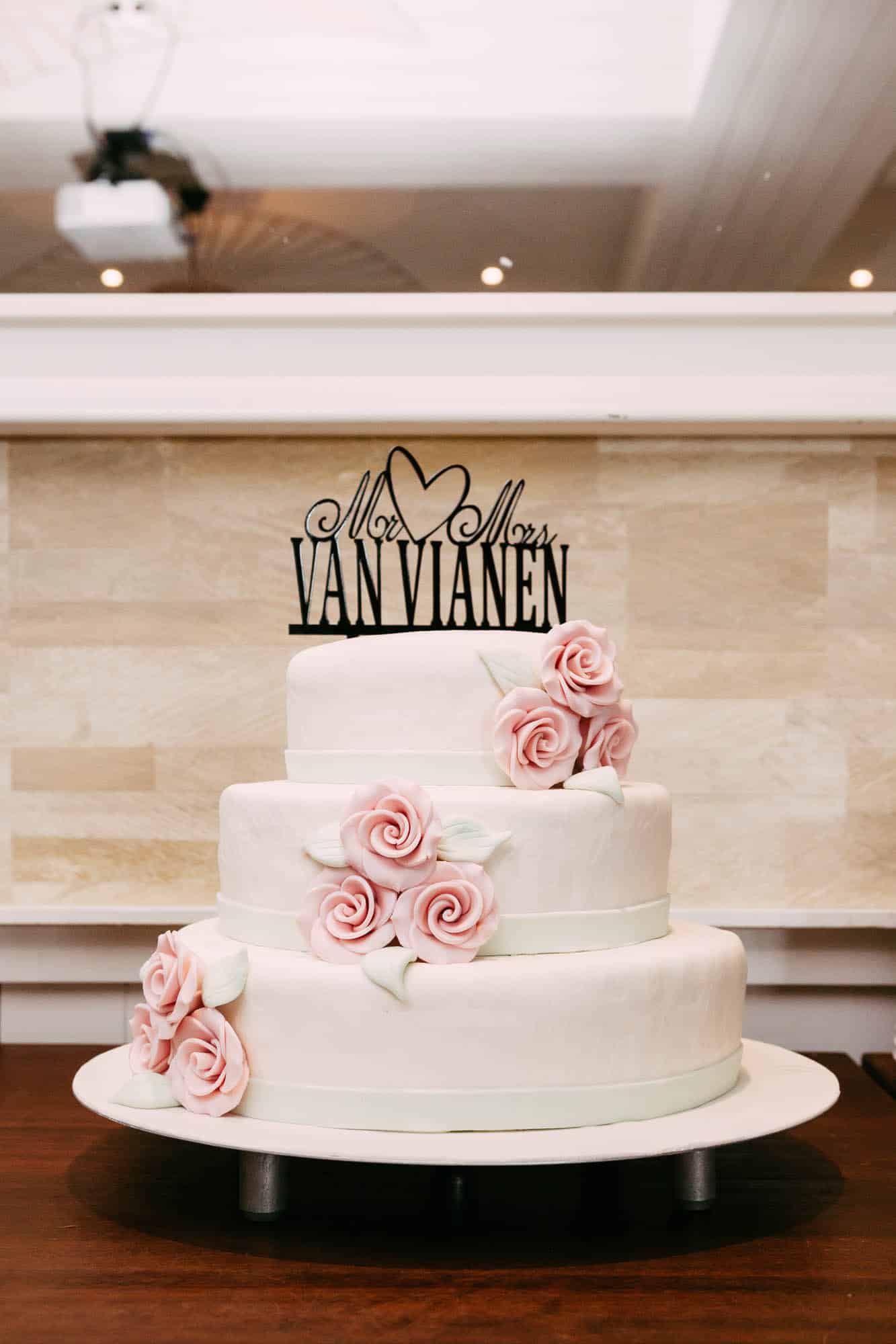 A wedding cake decorated with roses and a cake topper.
