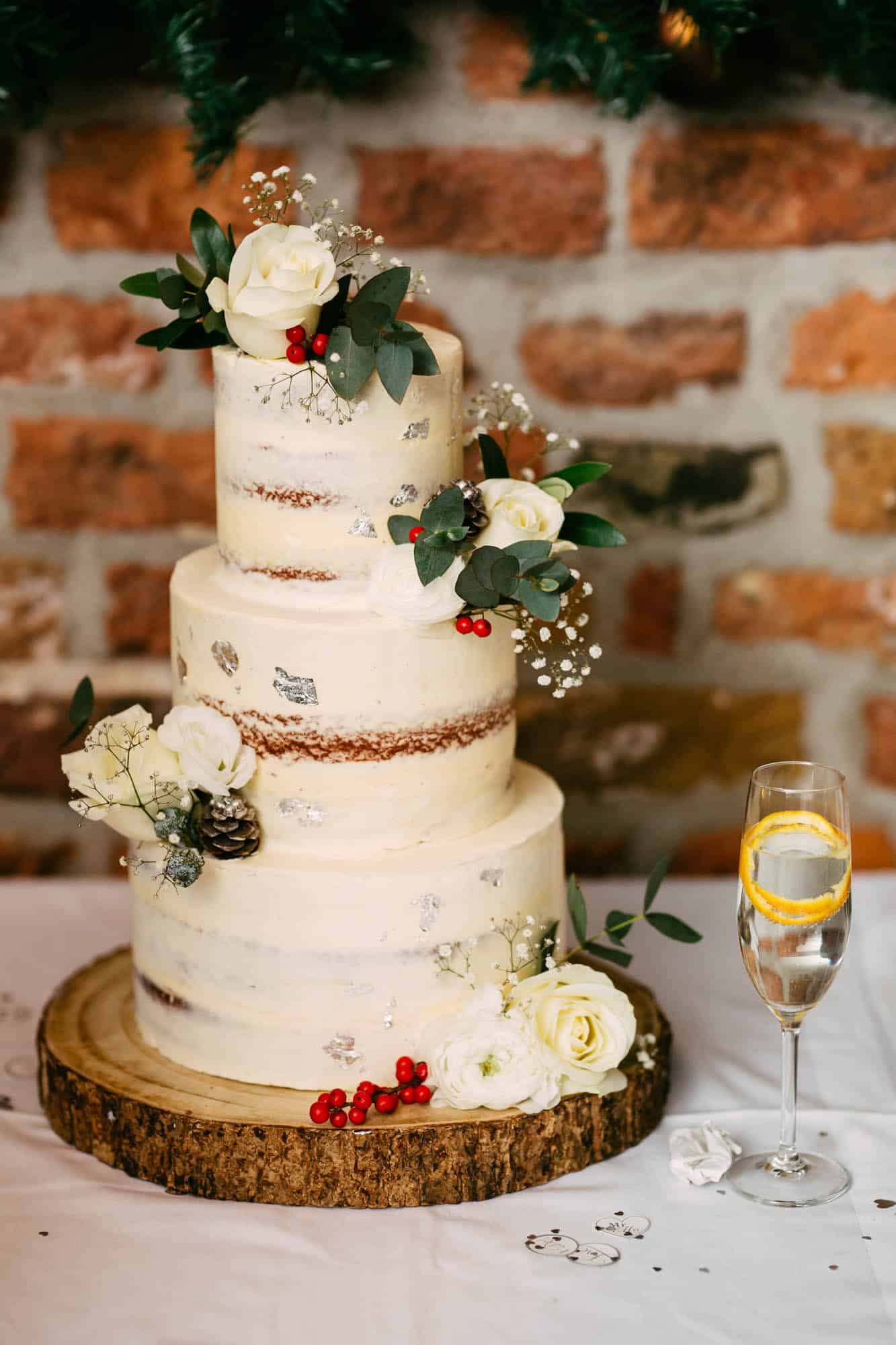 A wedding cake with flowers and a glass of wine.