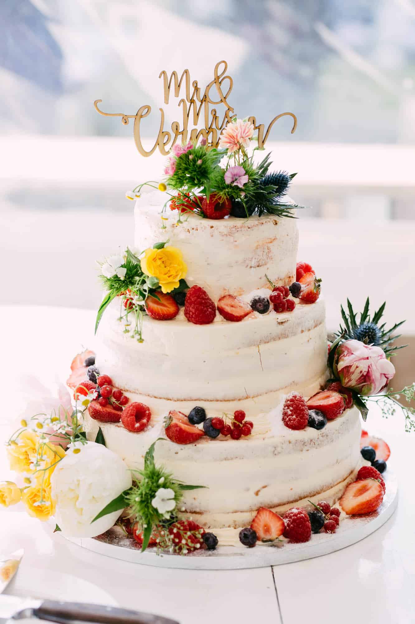 Naked wedding cake 3-layer with flowers and fruit.