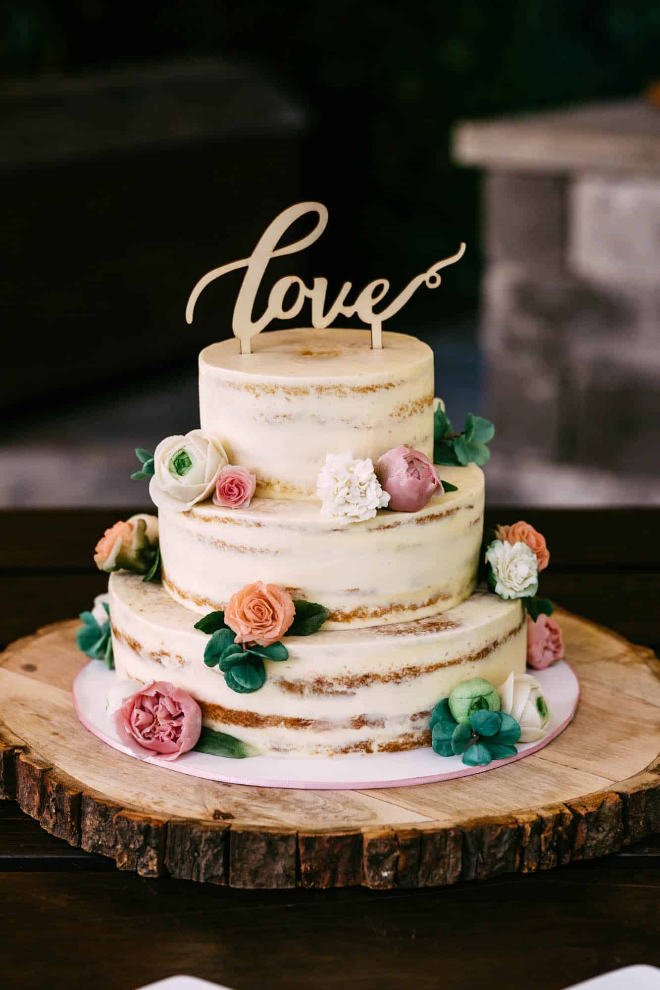 A wedding cake with the word love on top.