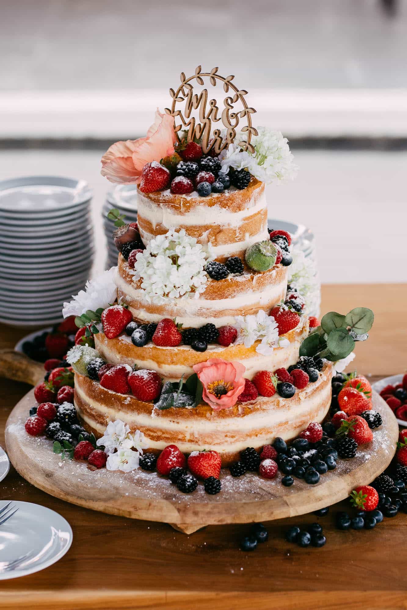 A wedding cake decorated with colourful berries and delicate flowers.