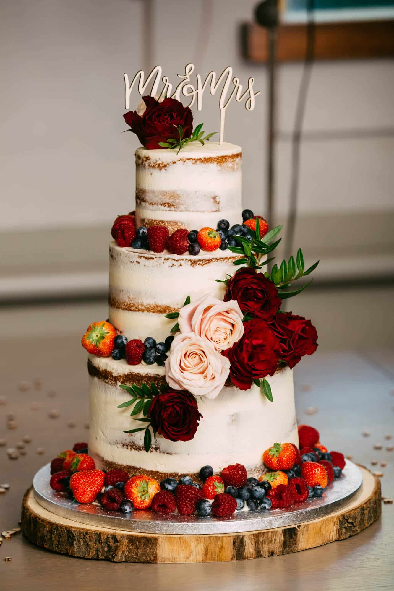 A wedding cake with berries and flowers on top.