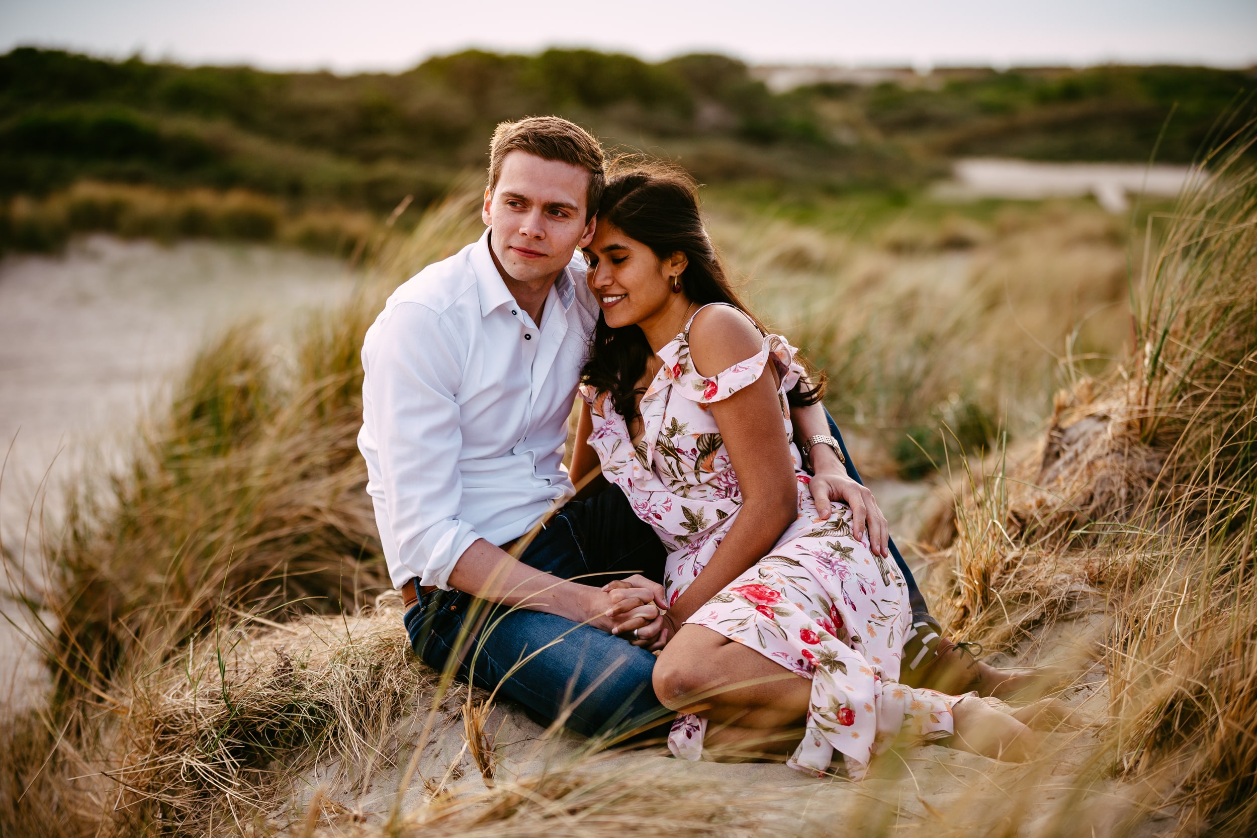 Een stel zit in het zand op een strand en ondergaat een relatietest.