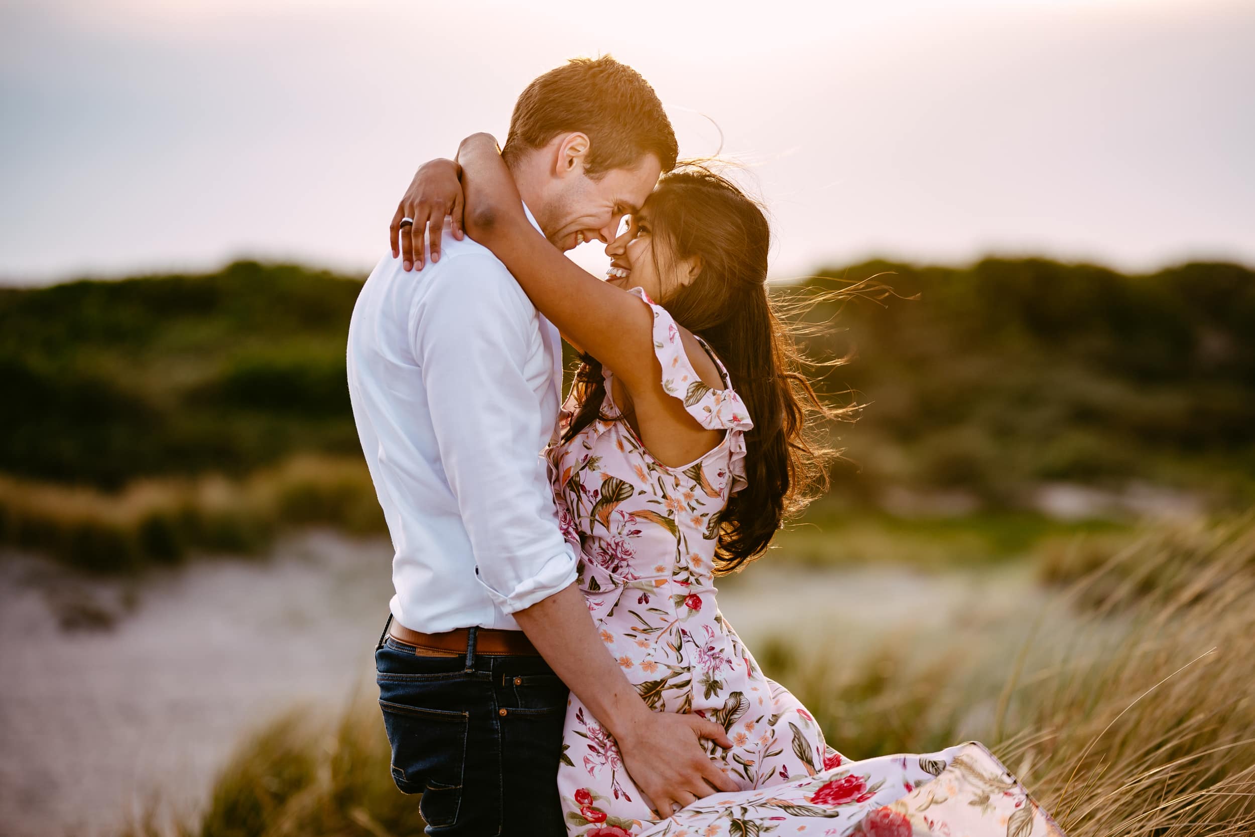 Een verloofd stel geniet van een romantische zonsondergangomhelzing op het zandstrand.