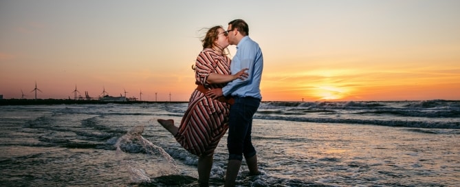 A passionate love shoot capturing a kissing couple in the ocean at sunset.