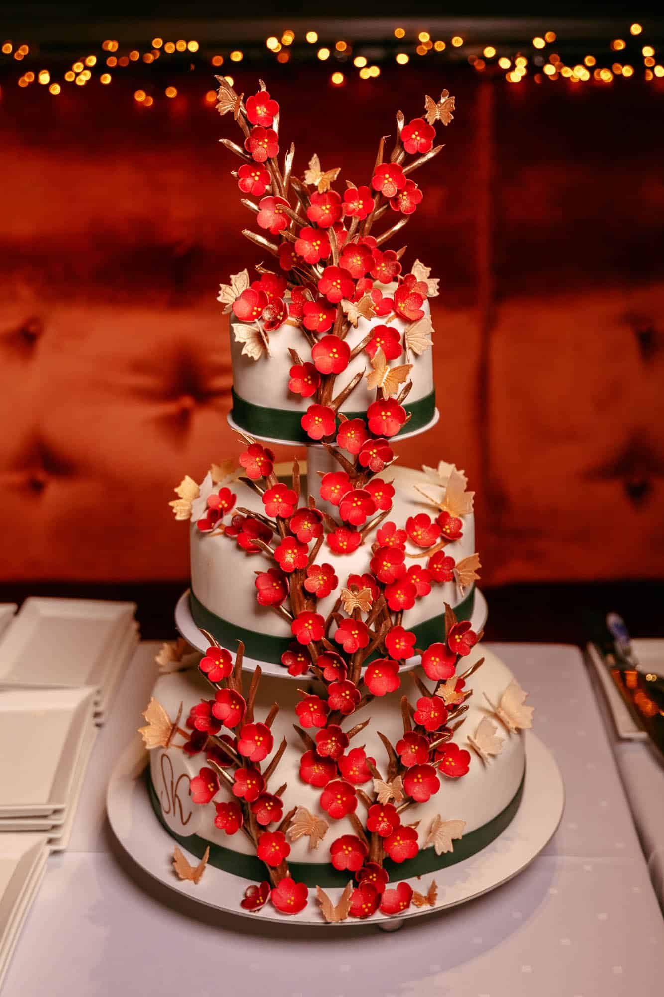 A wedding cake with red flowers on top.