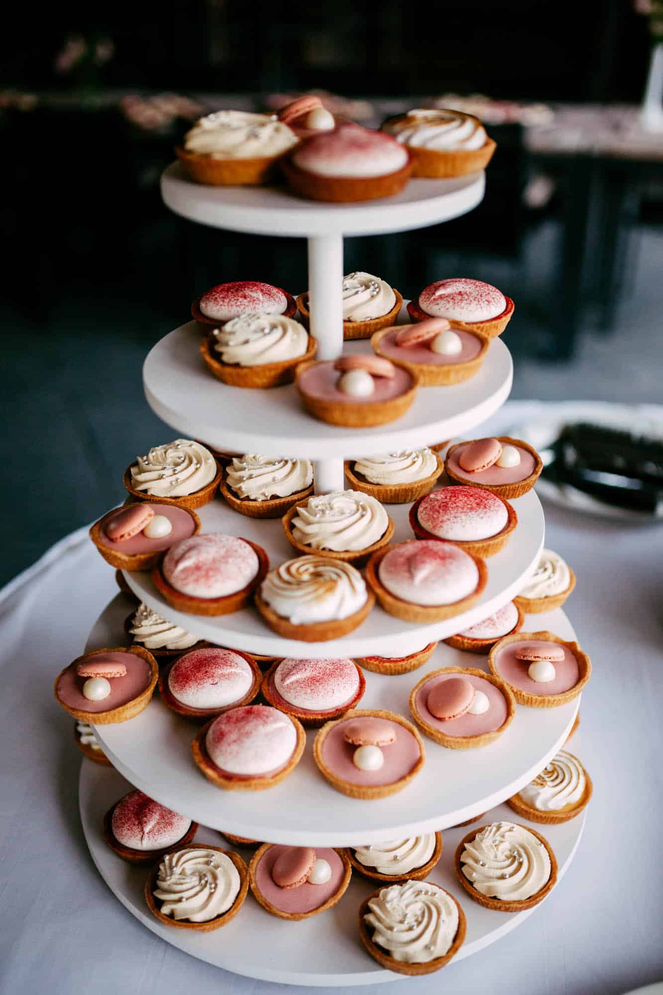 A three-tiered cake tray with wedding cakes on top.