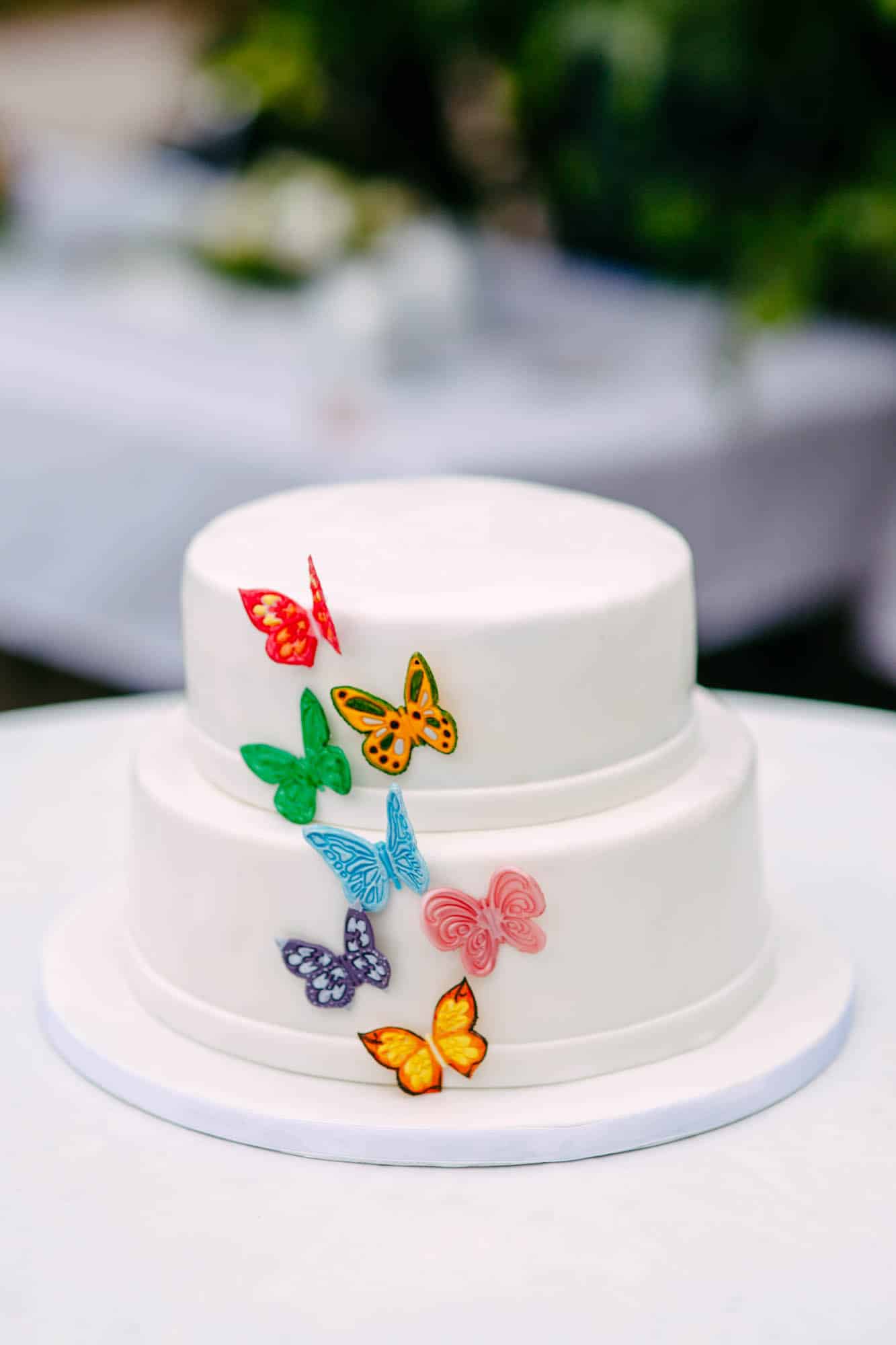 A white cake decorated with colourful butterflies.