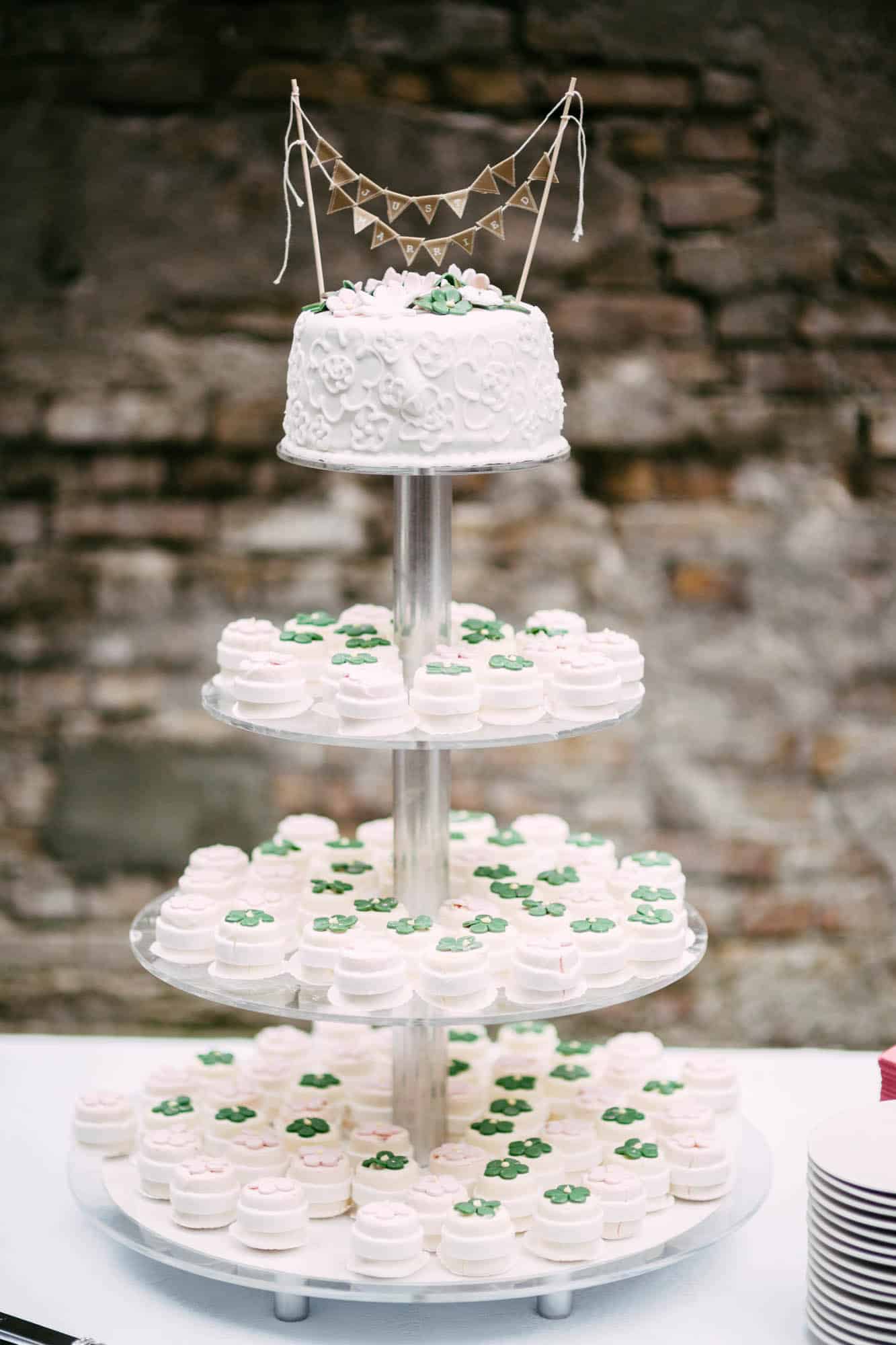 Een drielaagse taart gedecoreerd met groene en witte bruidstaarten.