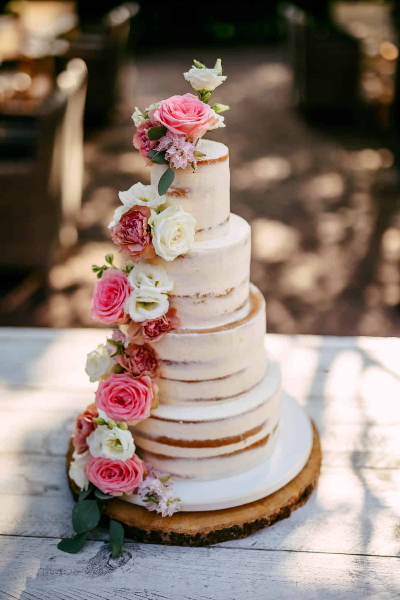 A wedding cake with pink flowers on top.