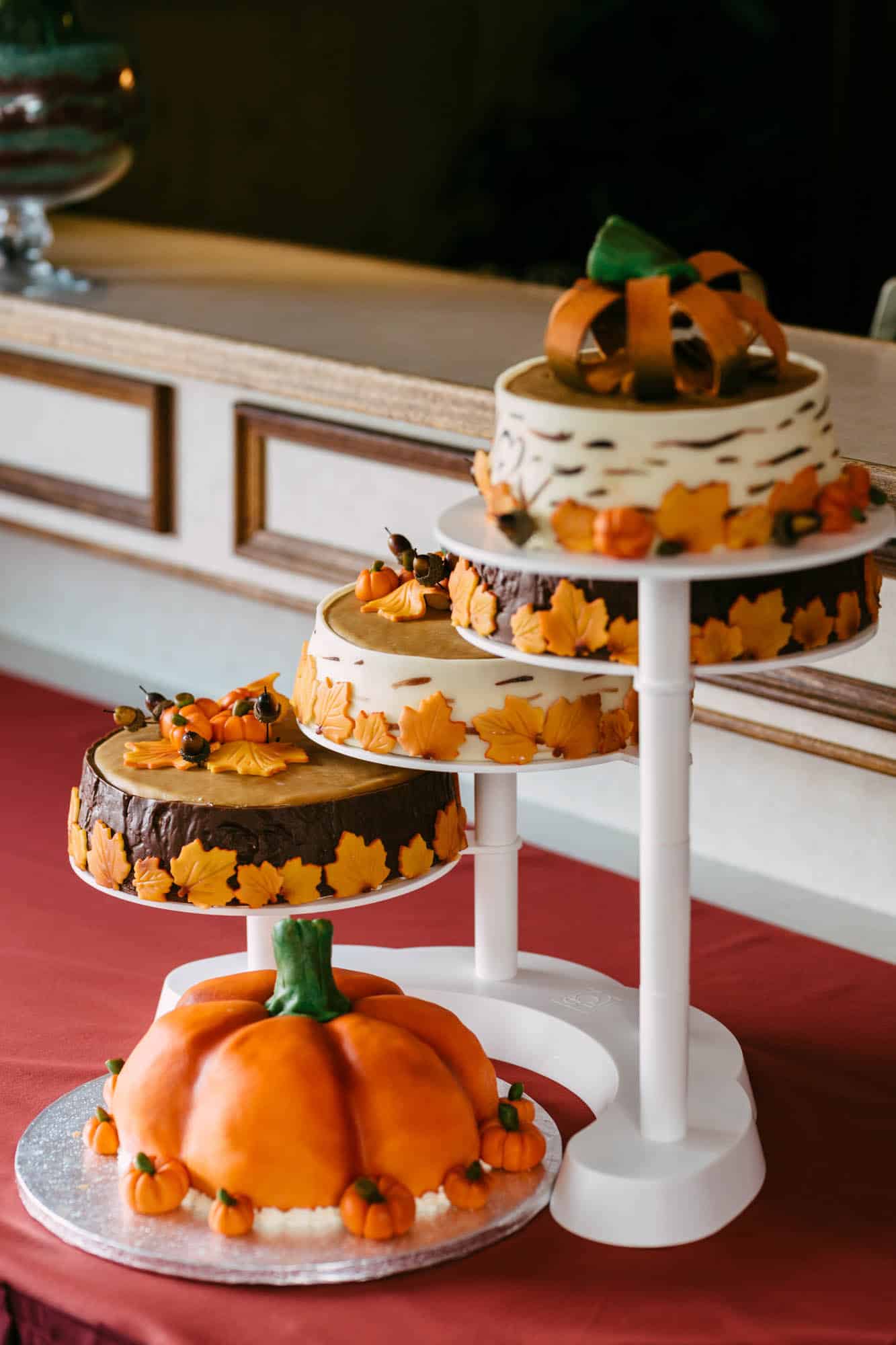A three-tier cake tray with pumpkins on top, perfect for displaying wedding cakes.