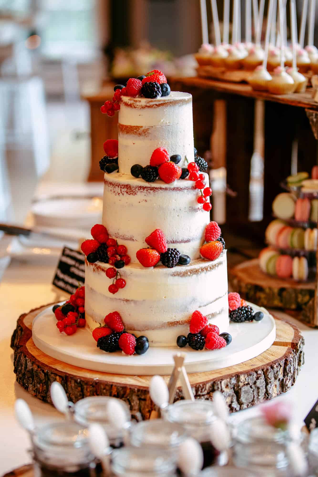 A three-layer wedding cake with berries on top.