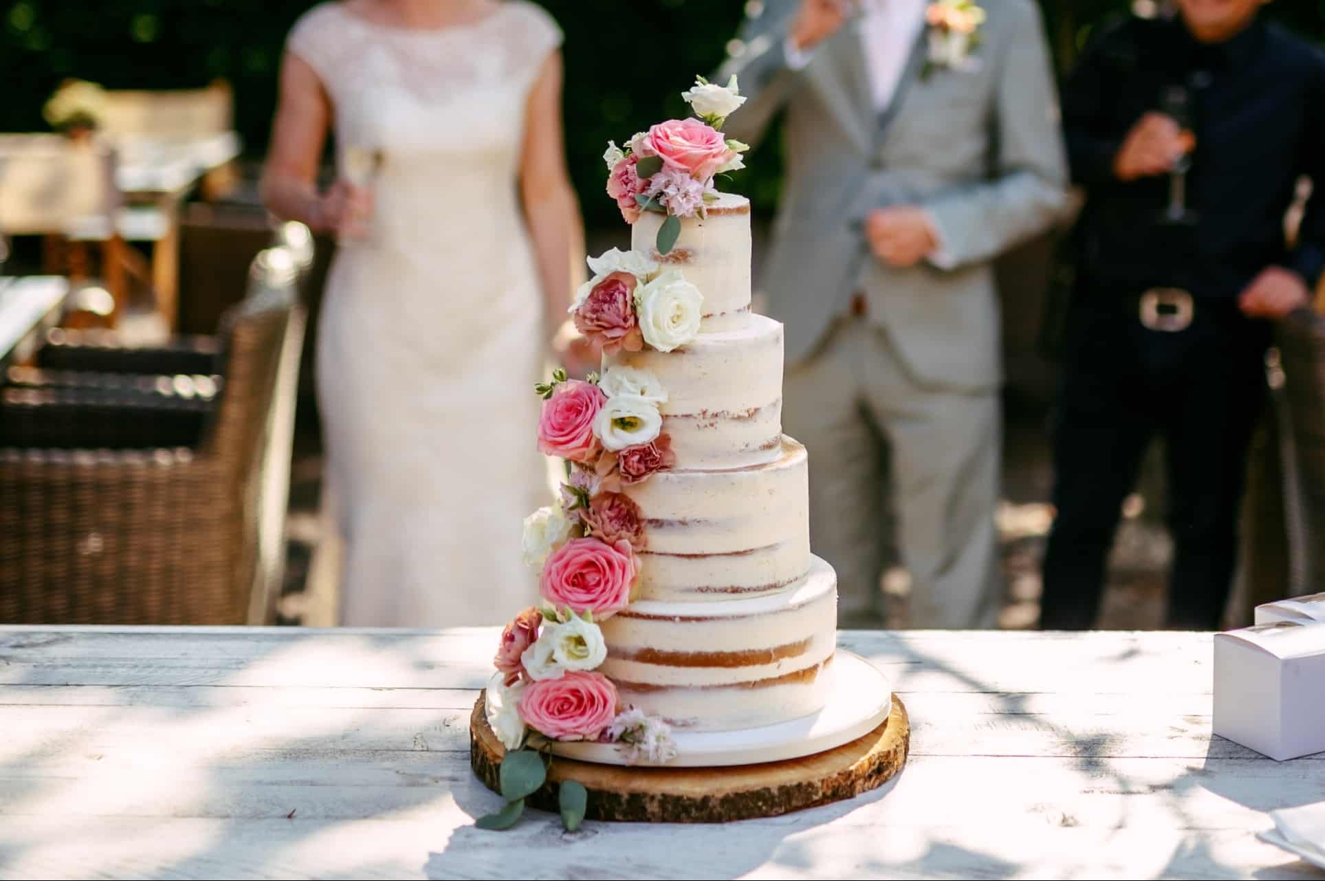 A wedding cake sitting on a wooden table.