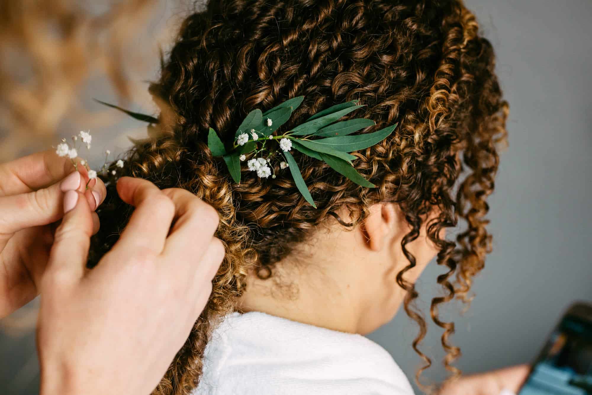 A woman has her hair cut in a bohemian wedding dress at a wedding.