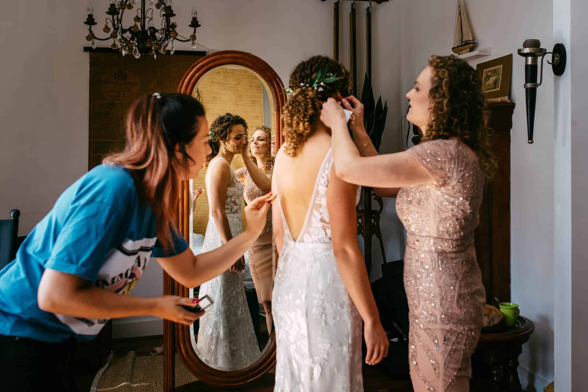 A bohemian bride getting ready in front of the mirror, dressed in a beautiful wedding dress.