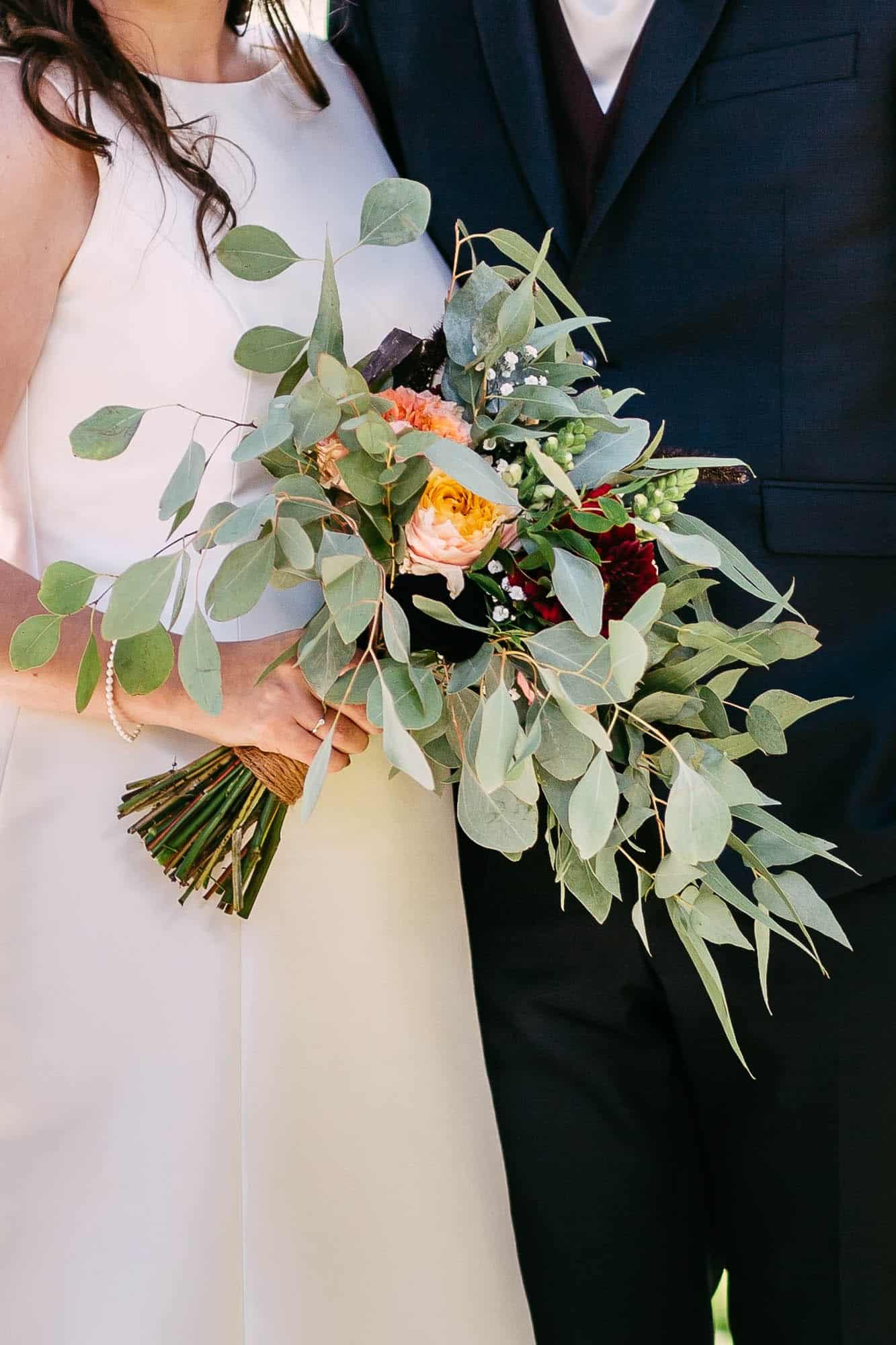 A bride and groom holding a wedding bouquet.