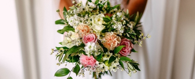 Wedding bouquet: A bride holding a wedding bouquet of pink and white flowers.