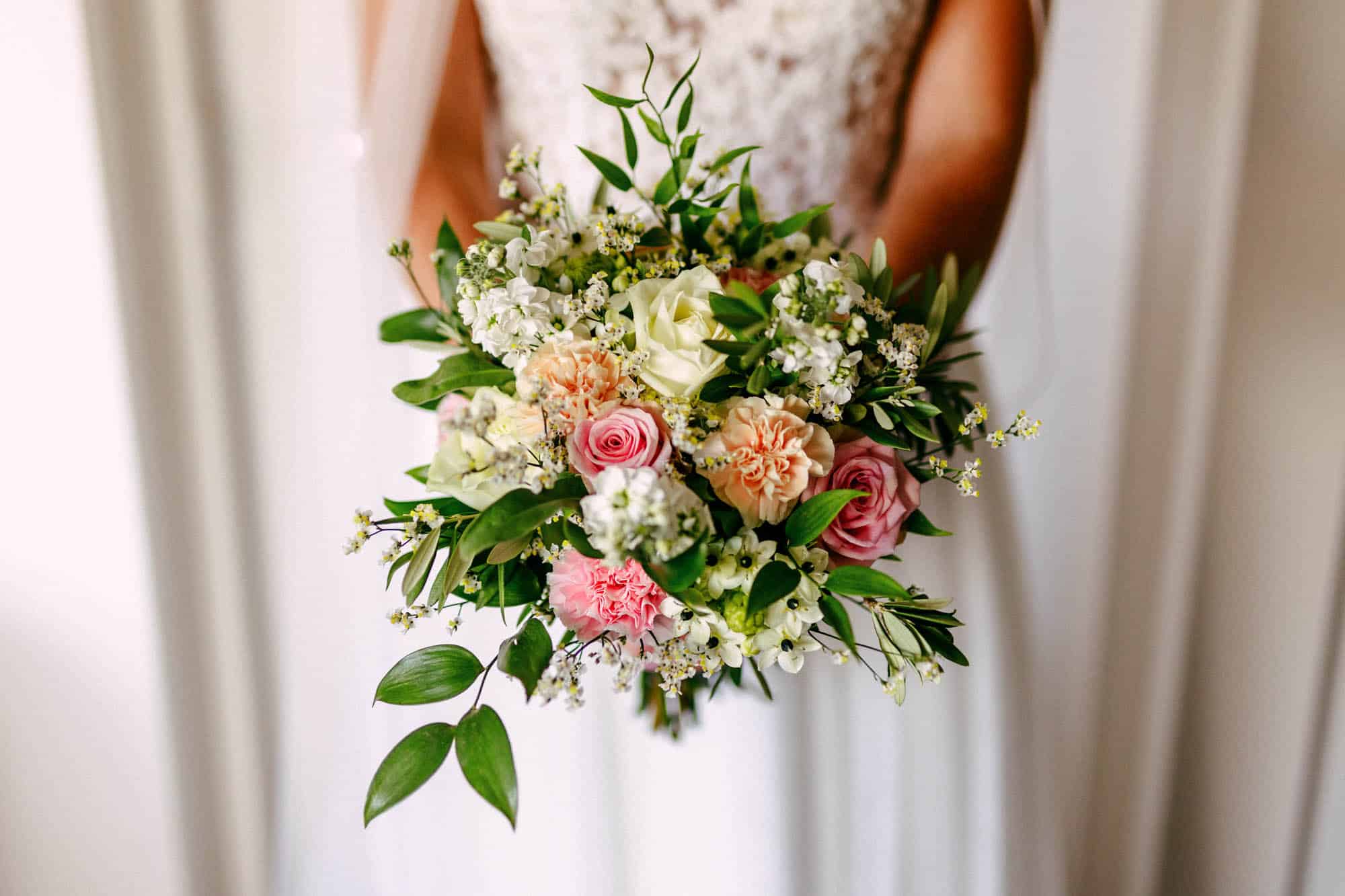 Wedding bouquet: A bride holding a wedding bouquet of pink and white flowers.