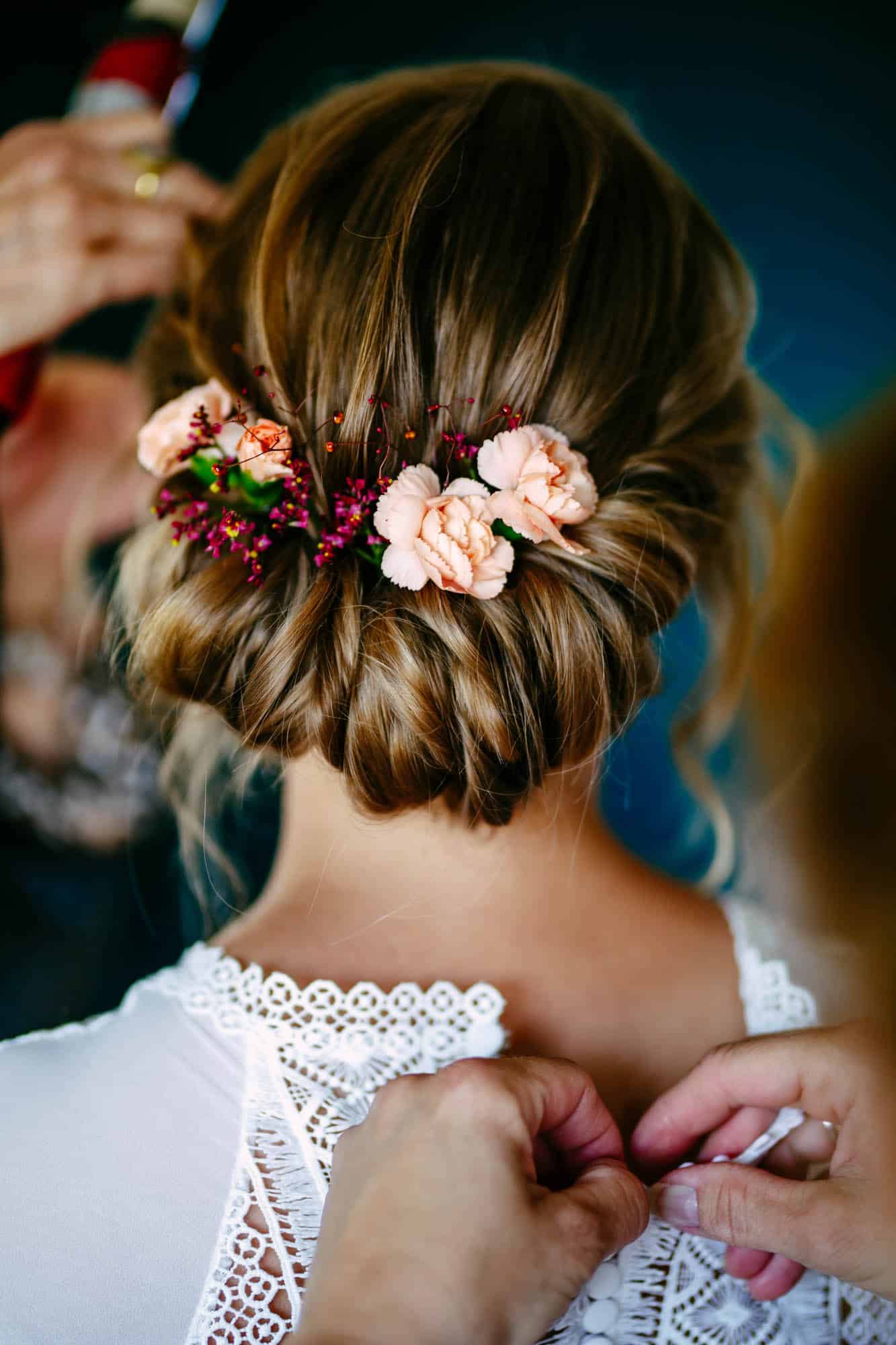 A bride having her hair done with bridal hairstyles and flowers in her hair.