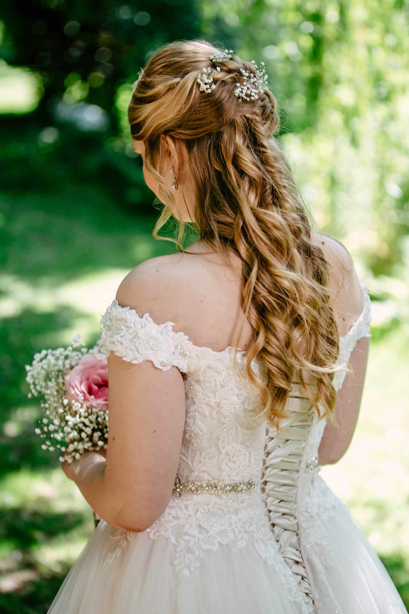A bride with bridal hairstyles in a beautiful wedding dress and flowers in her hair.